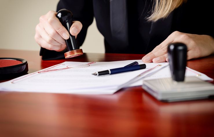 A notary public in a black blazer stamps a document.